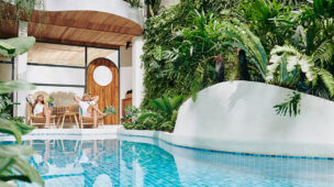 Casal relaxando em espreguiçadeiras ao lado de piscina cercada por vegetação tropical, aproveitando o conforto térmico garantido por trocador de calor Full Inverter.