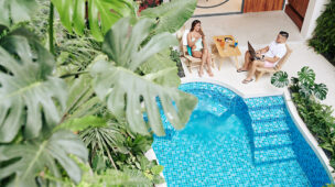 Casal relaxando ao lado de uma piscina em área tropical, aproveitando o conforto térmico proporcionado por uma bomba de calor Full Inverter.