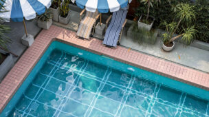 Piscina residencial com cadeiras e guarda-sóis à beira, ideal para momentos de lazer com conforto térmico garantido por bomba de calor Full Inverter.
