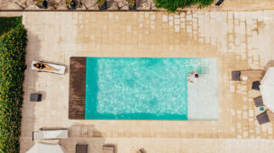 Vista aérea de uma piscina retangular com pessoas relaxando ao redor, representando lazer com conforto térmico proporcionado por bomba de calor Full Inverter.